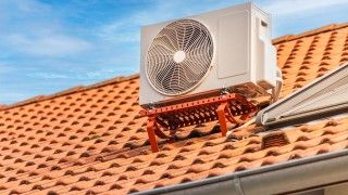 Klimatyzator zainstalowany na dachu, dachówka w kolorze cegły, słoneczny dzień