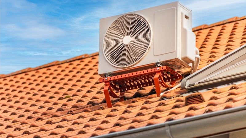 Klimatyzator zainstalowany na dachu, dachówka w kolorze cegły, słoneczny dzień