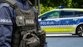 Funkcjonariusz Polskiej Policji i policyjny radiowóz marki Toyota.