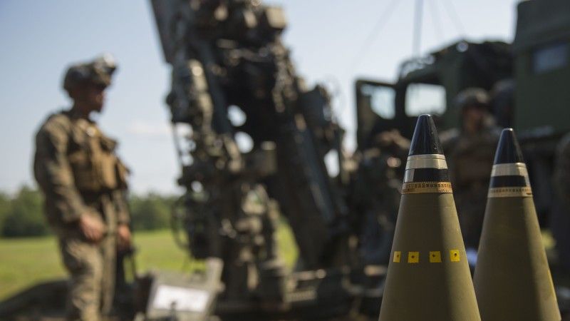 Pociski odłamkowo-burzące M795 kalibru 155 mm przygotowane do wystrzału podczas ćwiczeń Korpusu Piechoty Morskiej USA, czerwiec 2018 roku. W tle artylerzysta U.S. Marine Corps i 155 mm ciągniona haubica M777.