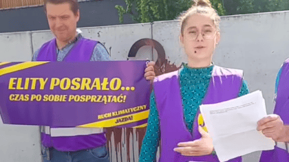 Aktywista trzyma baner z napisem: elity posrało... czas po sobie posprzątać, druga osoba przemawia do kamery