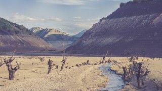 cracked-earth-and-sparse-water-in-mountainous-vall-2026-03-09-23-51-19-utc