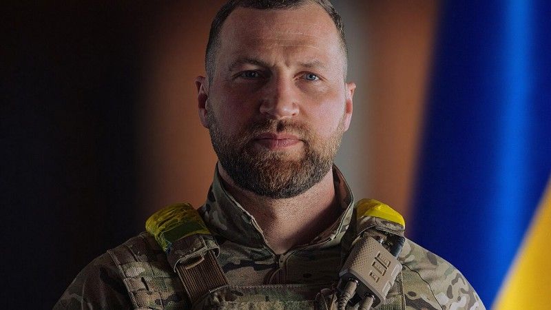 Jewhen Chmara, minister obrony Ukrainy na tle flagi państwowej