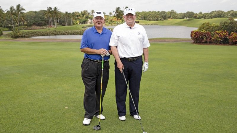 mężczyźni pozują do zdjęcia na polu golfowym, z kijami do golfa w dłoniach