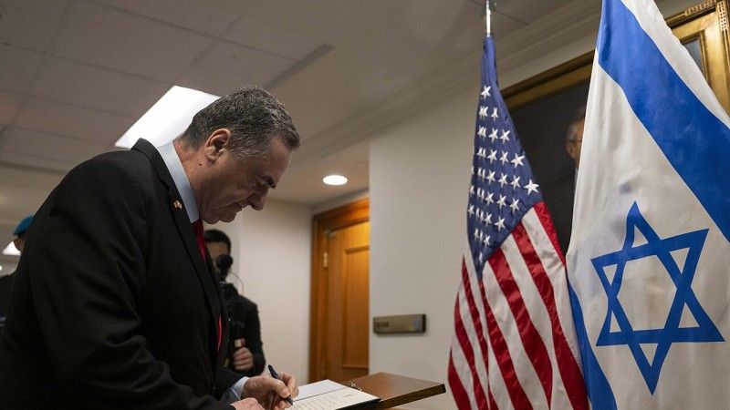 Israel Kac podpisuje dokument przy fladze USA i Izraela - zdjęcie poglądowe