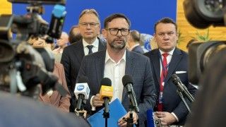 Daniel Obajtek mówi do mikrofonów, w tle inni europosłowie