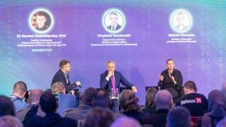 Dr Konrad Ciesiołkiewicz, Krzysztof Gawkowski i Barbara Nowacka na scenie Cyber24Days. Minister edukacji zabiera głos, na pierwszym planie widać publiczność.